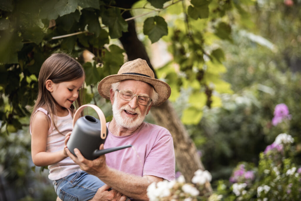 older male teaching a child how to water plants - a new vision of living